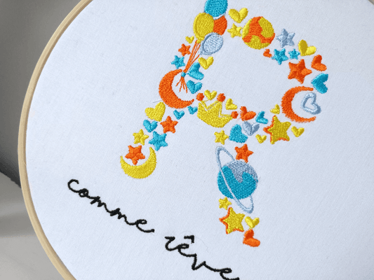 Tambourin brodé lettre orange bleu planète vue de près